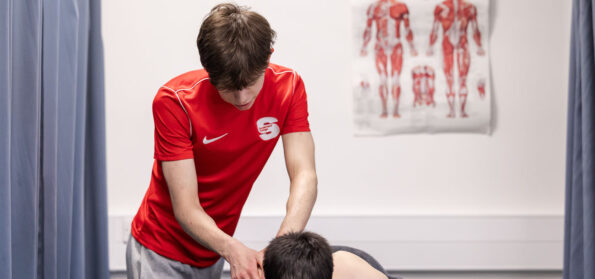 A Level 3 sports student performing a massage as part of their course.